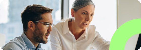 Two people working together looking at a monitor collaborating on a project.