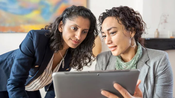 Two people working together on a tablet.